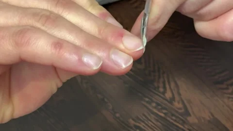 Man trims and files fingernails at table, personal grooming routine. Stock Footage 306530793