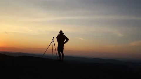 Man with tripod on the background of a bright sunset Stock Footage 62478261