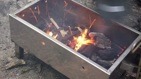 Man try to fire coal in barbecue with manual fan at forest Stock Footage 66255430