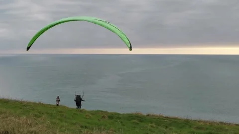 A man trying to catch a wind with his paraglide while woman is watching at Stock Footage 150153839