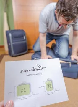 Man trying to close full hand luggage Stock Photos