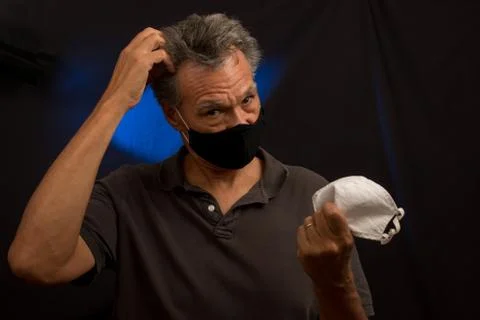 Man trying to decided what protective mask to wear Stock Photos