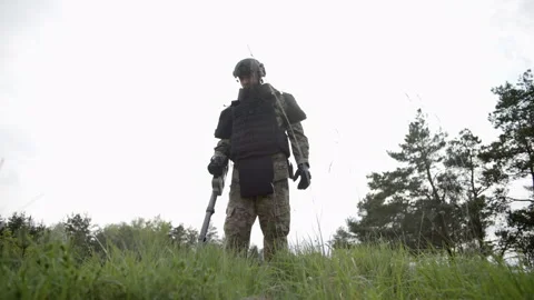 Man trying to detect mine in demining process in grass near the forest Video stock 240500342