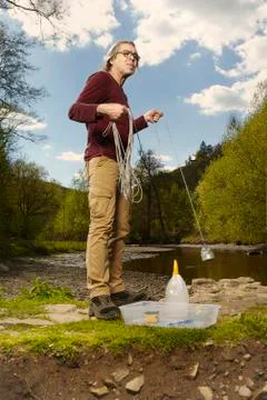 Man trying to explore river water with neodymium magnet to find something Stock Photos