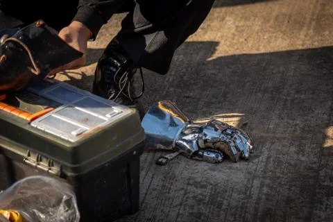 A man trying to fix his silver metal gauntlets, full of scratches due to battles Stock Photos