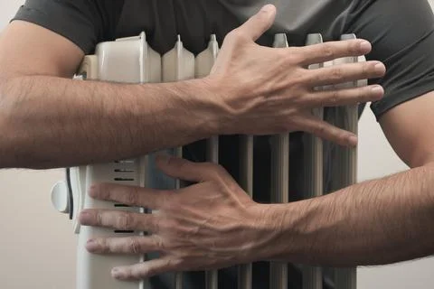 Man trying to keep warm hugging with the heater Stock Photos