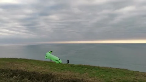 A man trying to lift the paraglide while woman is watching at the edge of Stock Footage 150153278