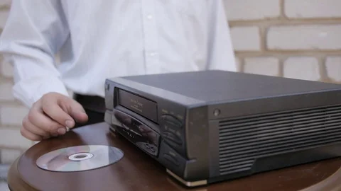 The man trying to load DVD disc to old video cassette VHS recorder. Stock Footage 69797288