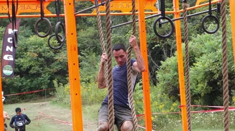 Man trying to pull himself across on rings and ropes Stock Footage 54136391