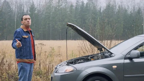 Man trying to stop the car on the road. Stressed male driver standing in front Stock Footage 142784159