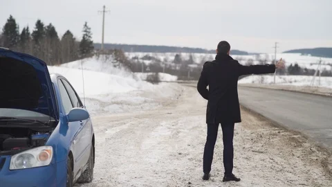 Man trying to stop someone on winter country road asking for help wit his broken 库存影片 103943176