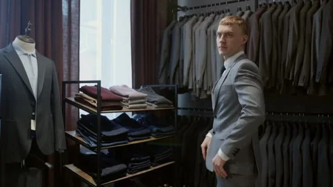 Man trying on suit and checking fit at fashion boutique Stock Footage 304520124