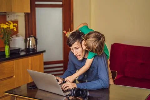 Man is trying to work from home because of the coronovirus epidemic, but his son Stock Photos