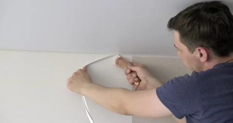 Man tucks frame into slots of stretched ceiling, decorative element, hides seam Stock Footage 131035099