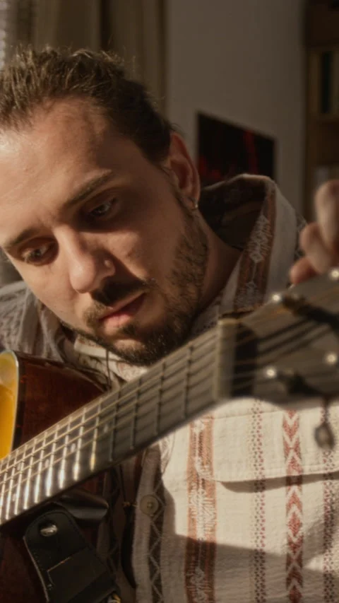 Man Tuning Acoustic Guitar Strings for Creative Hobby at Home Stock Footage 337542924