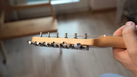 A man Tuning his guitar and playing it. Top lock tuners on double cut Stock Footage 340905085
