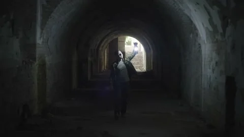 A man in a tunnel in a dungeon with a flashlight. A guy is looking for a person Stock Footage 217395052