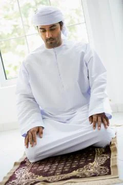 Man in turban praying on mat (high key) Stock Photos