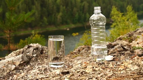 Man turn ON the appliance PH-meter in glass of water on mountain area. Slow-mo Stock Footage 94470167