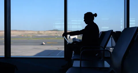 Man turn on laptop to join group meeting, silhouette at airport Stock Footage 259987262