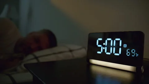 Man turning off alarm clock at 5,00 in bedroom. Early morning wake up moment Stock Footage 334022550