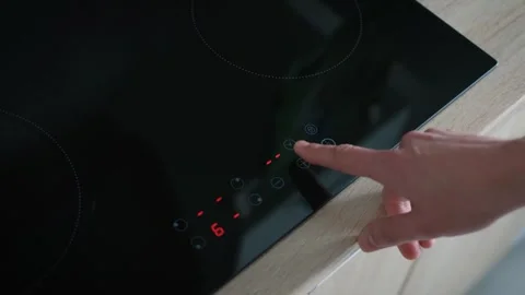 A man turning on and adjusting the heating level of a glass-ceramic stove Stock Footage 240434048