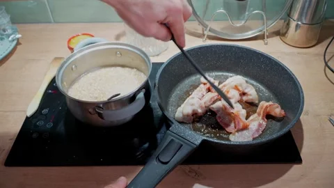 Man turning bacon strips in hot pan side view, kitchen cooking process with Stock Footage 333483620