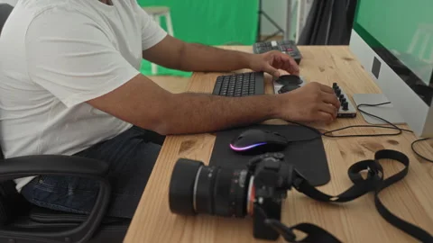 Man turning console knobs and using mouse with camera on wooden desk at com.. Stock Footage 347841698