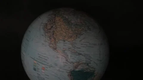 A man turning a globe in a dark background around with his hand and stoping on s Stock Footage 163767307