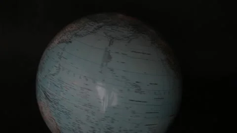 A man turning a globe in a dark background around with his hand and pointing to  Stock-Footage 163767380