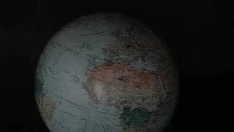 A man turning a globe in a dark background around with his hand and pointing to  Stock Footage 163767453