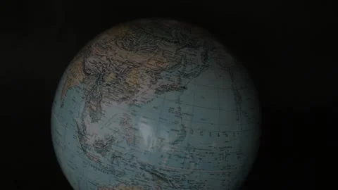 A man turning a globe in a dark background around with his hand and pointing to  Vídeo Stock 163773676