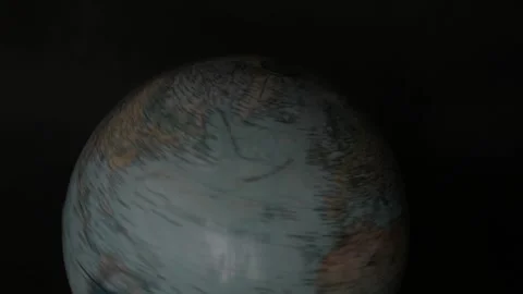 A man turning a globe in a dark background around with his hand and pointing to  Stock Footage 163773691