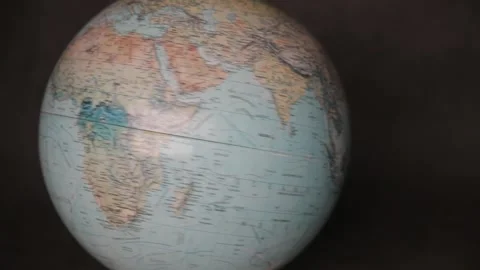 A man turning a globe in a dark background around with his hand and pointing to  Stock Footage 163773812