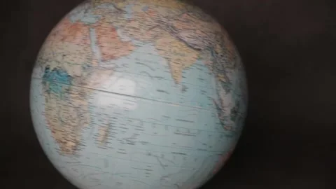A man turning a globe in a dark background around with his hand and pointing to  Stock Footage 163773821