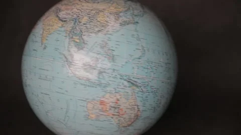 A man turning a globe in a dark background around with his hand and pointing to  Stock-Footage 163773835