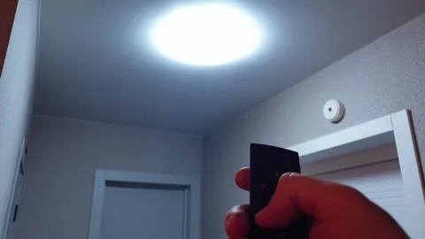 Man turning on the large round LED light in the apartment with remote contr.. Stock Footage 294718647