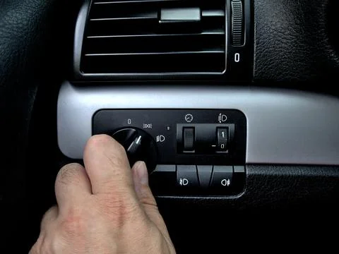 A man is turning on the light switch on the car dashboard Stock Photos
