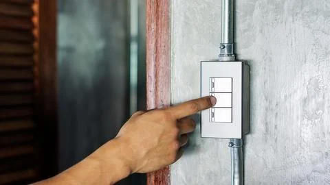 Man turning on or off on a light switch. Stock Photos
