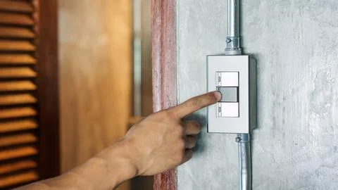 Man turning on or off on a light switch. Stock Photos