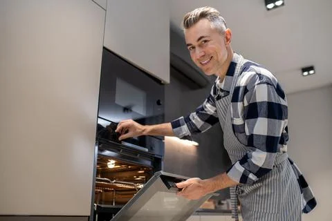 Man turning toggle switch of oven looking at camera Stock Photos