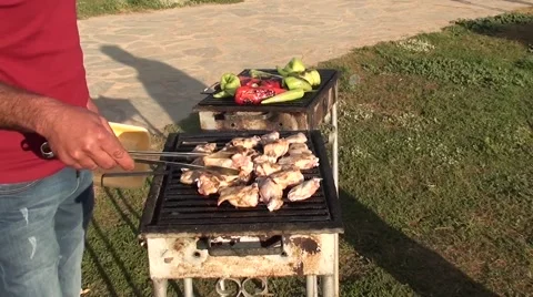 Man turning wings and vegetables on grill Stock Footage 49912596