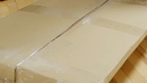 Man turns up and opens cardboard package sitting on floor Video stock 304397882