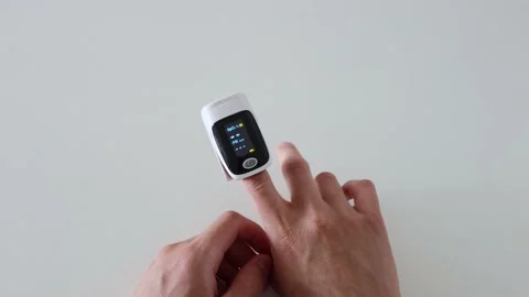 Man turns on and puts pulse oximeter on his finger Stock Footage 200771120