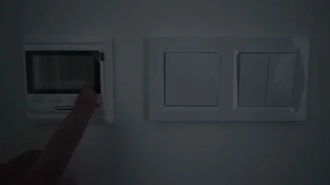 Man turns on and regulates the temperature of the warm floor on the regulator Stock-Footage 122087590
