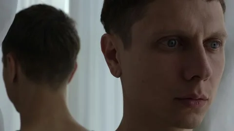 Man turns back to mirror, avoiding his own reflection. Symbolic struggle with 스톡 동영상 311048682