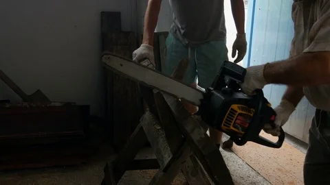Man turns on the chainsaw and saws the planks 스톡 동영상 80190502