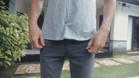 Man Turns the Empty Pockets of His Jeans in front of the house.. No Money Stock Footage 100131293