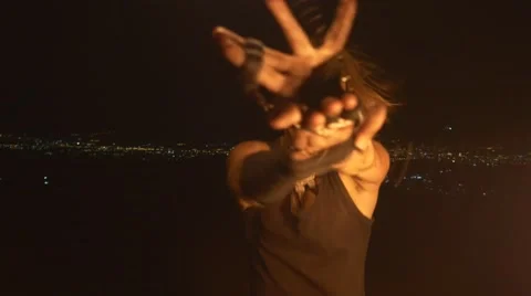 Man turns fire poi in front of city lights Video stock 67628889
