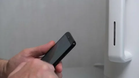 The man turns on the kettle using an application on his smartphone. Smart home. Video stock 167358748